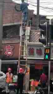 Funny China Shanghai Electrical Work in Street no hardhat on ladder